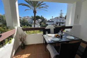 stół i krzesła na balkonie z palmą w obiekcie Costalita - 2 bedroom apartment 350m from the beach w mieście Estepona