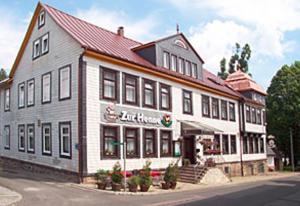 a large white building with a store on a street at Hotel Zur Henne in Schmiedefeld am Rennsteig