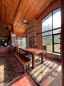 a dining room with a wooden table in a room with windows at Deumadi Mountain Cottage in Pokhara