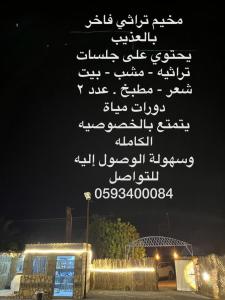 مخيم يمك دروبي في العلا: علامة مكتوبة باللغة العربية فوق مبنى في الليل