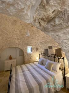1 dormitorio con 1 cama en una pared de piedra en Trulli Casalina, en Cisternino