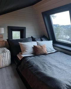 ein Schlafzimmer mit einem Bett mit Kissen und einem Fenster in der Unterkunft Mikrohyttene Moen Ranch in Kragerø