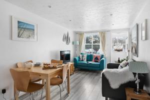 a living room with a table and a blue couch at Pippin Cottage - Character cottage with the spirit of the sea in Salcombe