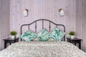 ein Bett mit grünen und weißen Kissen und zwei Tische in der Unterkunft Bajorų sodyba in Padvarionys