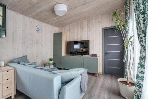 uma sala de estar com um sofá azul e uma televisão em Bajorų sodyba em Padvarionys