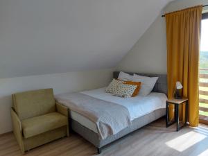 a bedroom with a bed and a chair and a window at Barwald Hills in Wadowice