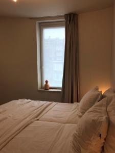 a bedroom with a white bed with a window at White Princess - Lehouck in Koksijde