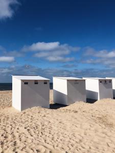 tres estructuras blancas sentadas en una playa de arena en White Princess - Lehouck, en Koksijde
