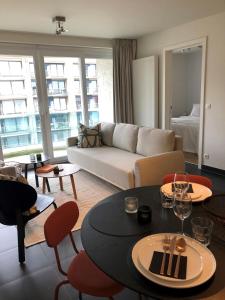 Una sala de estar con un sofá, una mesa y sillas. en White Princess - Lehouck, en Koksijde