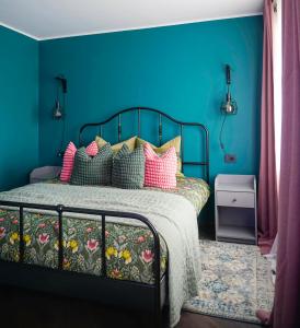 ein blaues Schlafzimmer mit einem Bett mit bunten Kissen in der Unterkunft Apartment Secret in Jonava