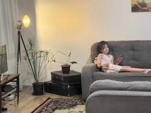 ein junges Mädchen auf einer Couch im Wohnzimmer in der Unterkunft Koonjak in Buxoro