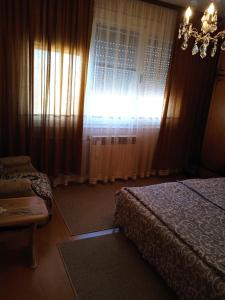 a bedroom with a bed and a chandelier and curtains at Apartman Nikolic in Bor