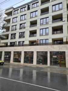 a large white building with many windows on a street at Augusta Apartment in Stara Zagora