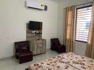 a bedroom with a bed and two chairs and a tv at Staywell360 in Chandīgarh
