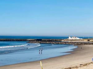 a beach with people walking on the sand and the ocean at Alamedastudio in Vila do Conde