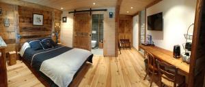 um quarto com uma cama num quarto com paredes de madeira em Atelier des Sapins Blancs (chambre double) em Vacheresse