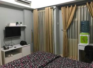 1 dormitorio con 1 cama, TV y cortinas en MARGONDA RESIDENCE 3 en Kemirimuka Dua