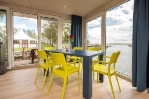 a dining room with yellow chairs and a table and windows at Hafenresort Karnin _ Hausboot Selma in Karnin (Usedom)