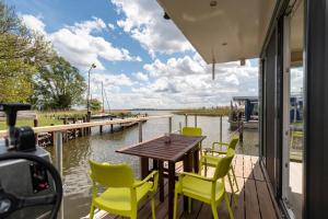 una mesa y sillas en un porche con vistas al agua en Hafenresort Karnin _ Hausboot Selma en Karnin