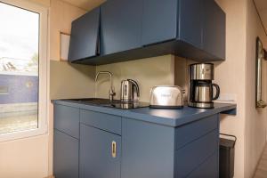 una cocina con armarios azules y un fregadero con un aparato en Hafenresort Karnin _ Hausboot Selma en Karnin