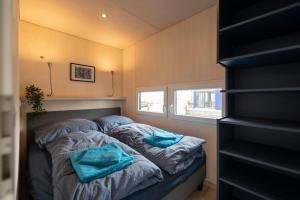 a small bedroom with two blue towels on a bed at Hafenresort Karnin _ Hausboot Selma in Karnin