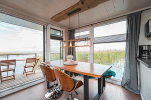 una sala da pranzo con tavolo, sedie e finestre di Hafenresort Karnin _ Hausboot Silv a Karnin
