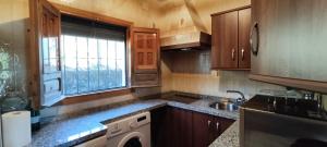 una cocina con armarios de madera, lavadora y fregadero en Finca el Berezal, en Aracena