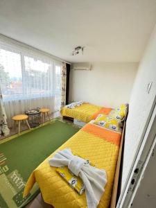 een slaapkamer met 2 bedden en een groen tapijt bij Апартамент във вила Артемида in Varna