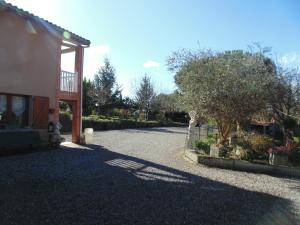 a gravel driveway next to a house with a tree at LOGIS DE NANO in Gratens