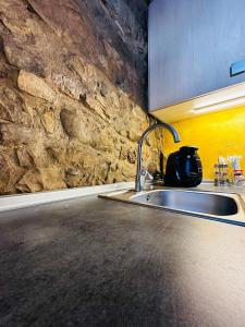 uma cozinha com um lavatório e uma parede de pedra em Alojamiento La Milana em La Robla