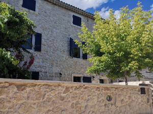 サン・レミ・ド・プロヴァンスにあるNamaste Home, charming holiday home in Saint Rémy de Provence - South of Franceの黒窓と木々のある石造りの建物