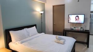 1 dormitorio con 1 cama blanca y TV de pantalla plana en Palm Tree Villas Condominium by Beth, en Manila