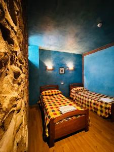 duas camas num quarto com uma parede de pedra em Alojamiento La Milana em La Robla