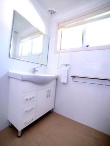 Baño blanco con lavabo y espejo en Close to lake, golf & beach, perfect for longer stays, en Toukley
