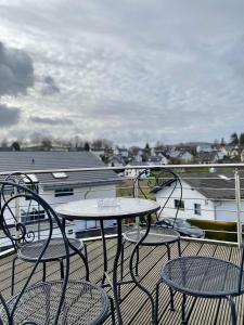 a patio with three chairs and a table on a balcony at Moderne Ferienwohnung Seeblick in Freudenberg