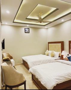 a bedroom with two beds and a ceiling at Grand Luxury Hotel Multan in Multan