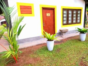 a house with two potted plants in front of a door at Coco Garden Villas 1 in Hikkaduwa