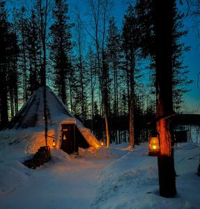 une tente en tipi dans la neige la nuit dans l'établissement Skyfire Village Igloos, à Rovaniemi