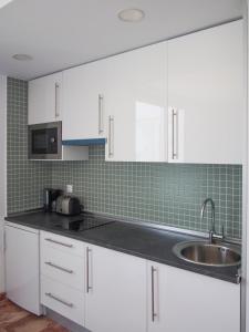 a kitchen with white cabinets and a sink at Apartamentos Embalse de Orellana in Orellana la Vieja