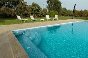 a swimming pool with four chairs next to it at Casa Rural en Rupià con piscina in Rupiá