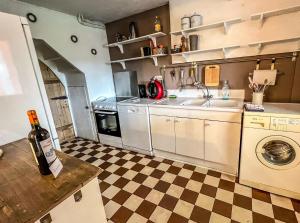 cocina con suelo a cuadros y lavamanos en La Maison Hôte, gîte de charme en bord de Semois, en Bouillon