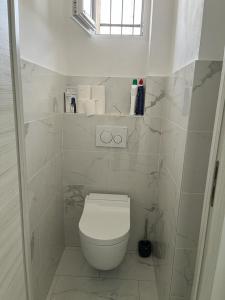 a white bathroom with a toilet and a window at Le Grand Bleu in Nice +12 photos