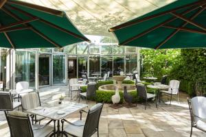 eine Terrasse mit Tischen, Stühlen und einem Brunnen in der Unterkunft Engimatt City & Garden Hotel in Zürich