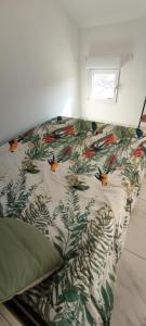 a bed with a comforter with birds on it at Appartement au coeur des rizières in Salin-de-Giraud