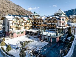 ein großes Gebäude mit Schnee auf dem Boden in der Unterkunft Tevini Dolomites Charming Hotel in Commezzadura