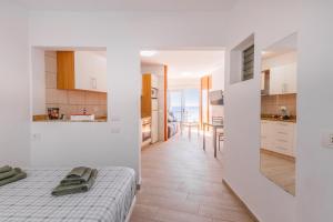 a white room with a bed and a kitchen at Spacious studio next to the sea with stunning views in Santa Cruz de Tenerife