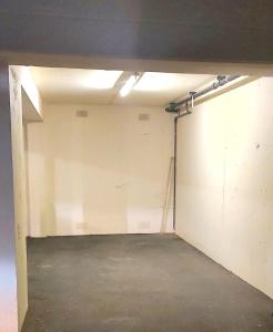 un garage con parete bianca e soffitto di Cosy 2 bedroom appartment with gated parking by River Thames a Kingston upon Thames