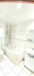 a bathroom with a tub and a toilet and a sink at Cosy 2 bedroom appartment with gated parking by River Thames in Kingston upon Thames