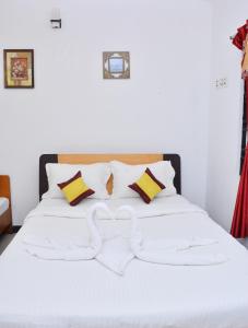 uma cama branca com lençóis e almofadas brancos em TGT Holidays Yercaud em Yercaud
