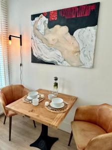einem Esstisch mit 2 Stühlen und einem Gemälde in der Unterkunft Oranje Nassau aan Zee Appartement in Zandvoort